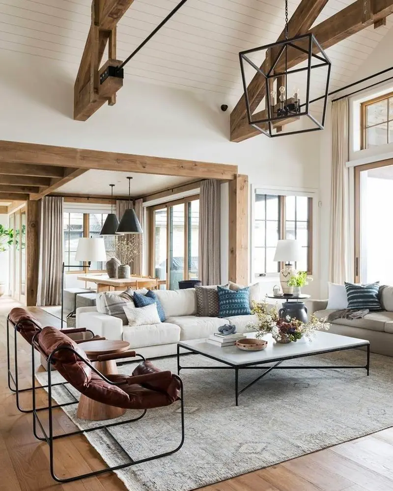 Leather sling chairs, a large square coffee table and an iron lantern pendant under vaulted beams