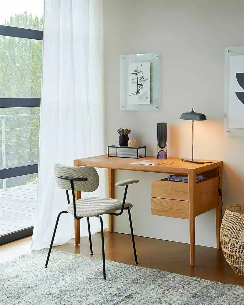 Wood desk with black table lamp, gray chair, sheer curtains and framed botanical print