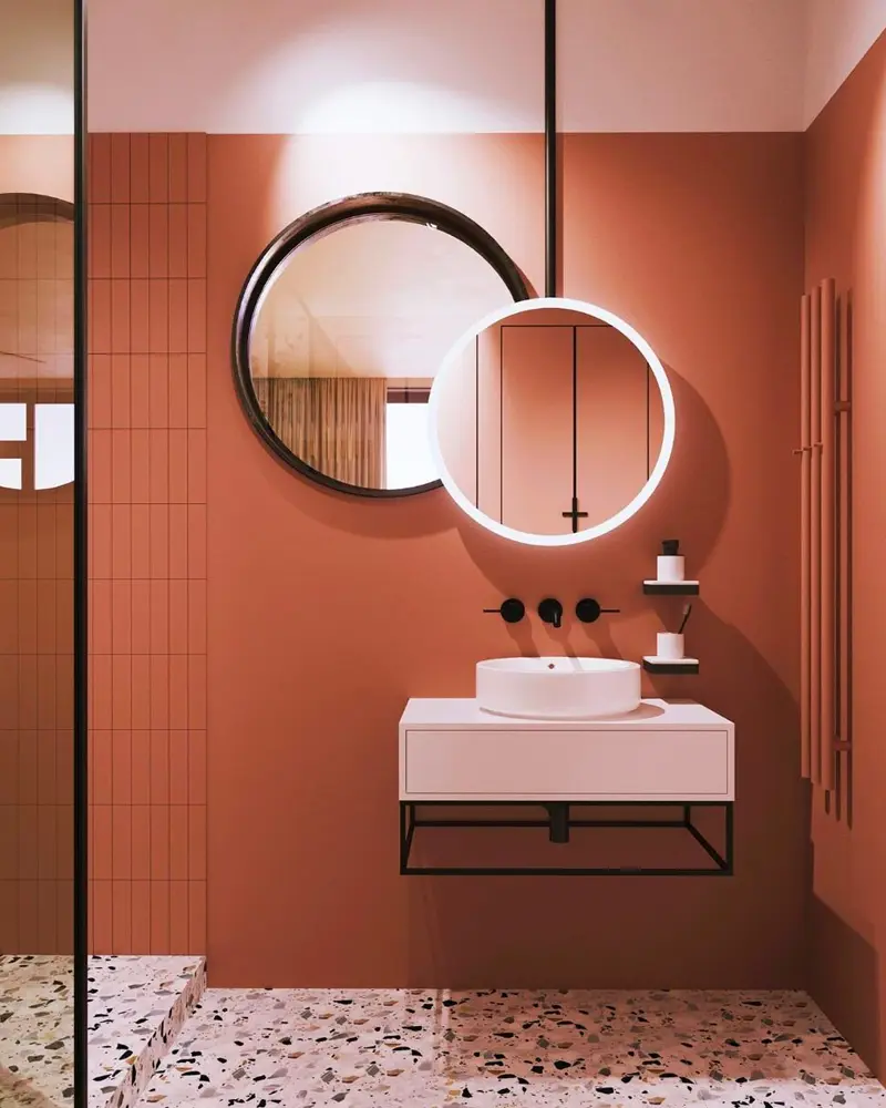 Terracotta bathroom with tiled shower, floating sink, round mirrors and terrazzo floor