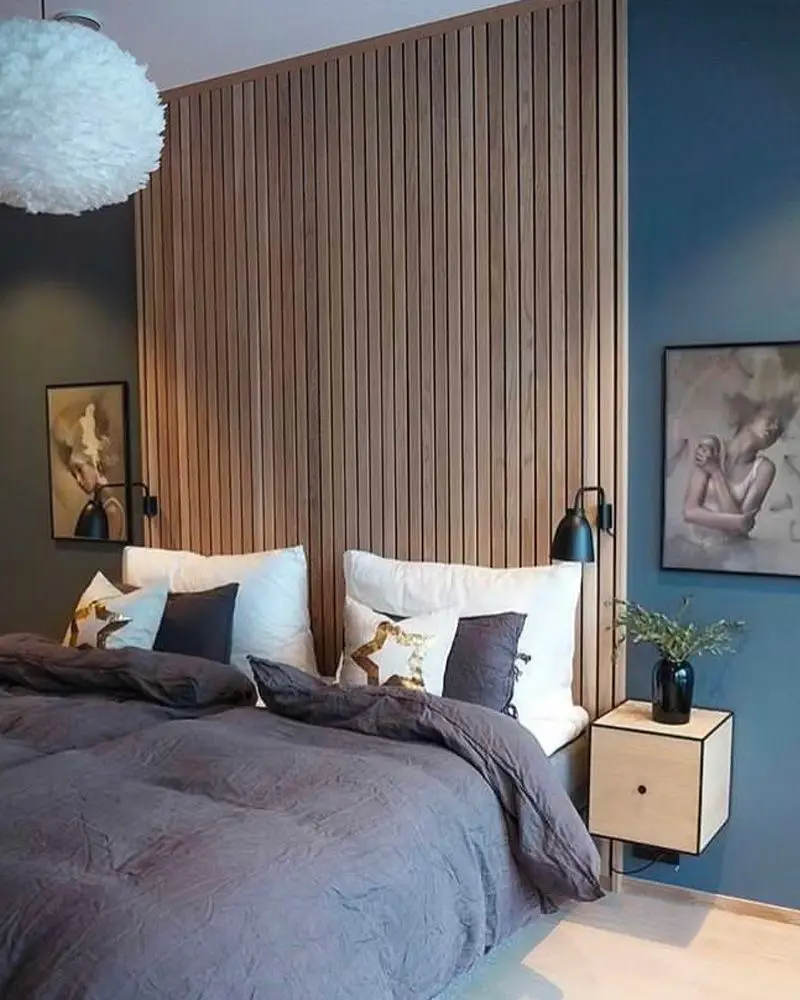 Bedroom with a slatted wood wall beside a dark blue wall and navy bedding