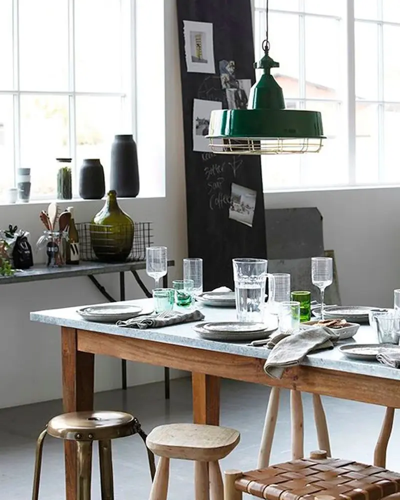 Wood table with a zinc top, a green enamel pendant, wood stools and a chalkboard wall
