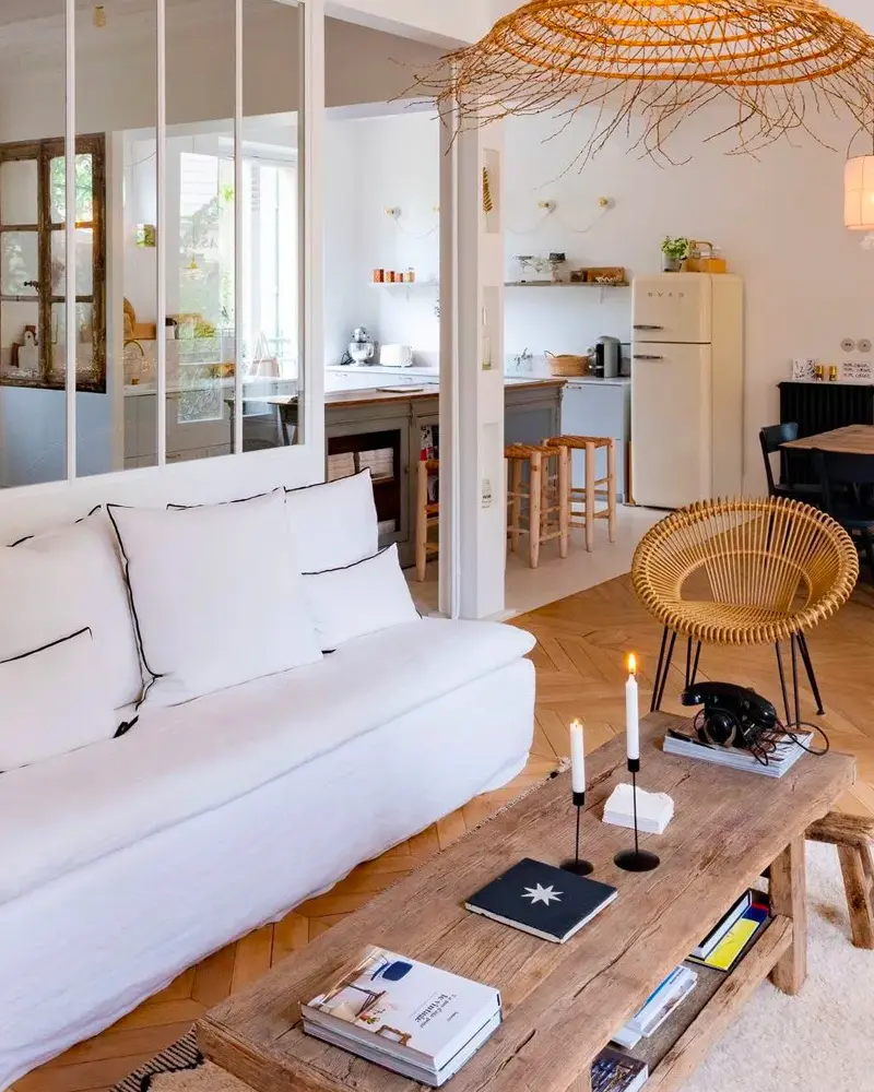 White sofa, long wood coffee table with candles, woven pendant and glass partition to the kitchen