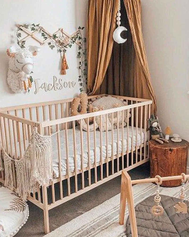Boho wooden crib with macrame, felt garland, moon mobile and tan curtain draped behind