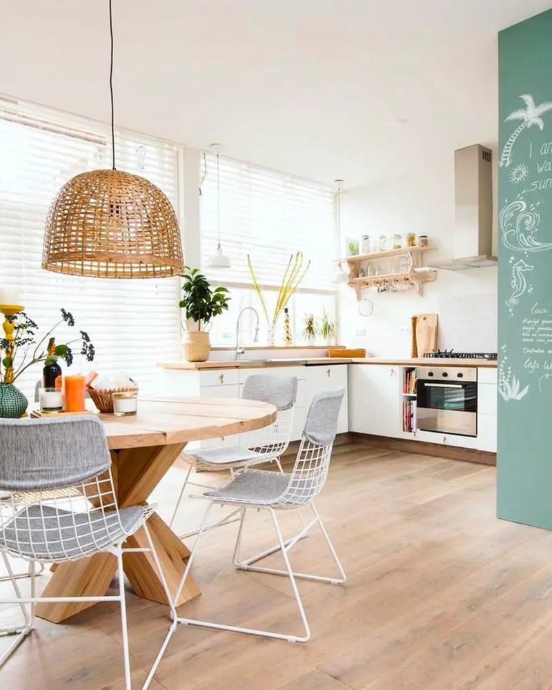 Bright kitchen with woven rattan pendant over a round wood table and white wire chairs