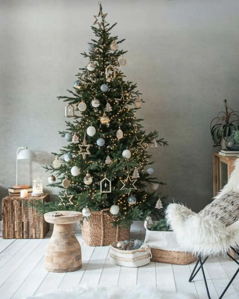 Christmas tree with white ornaments and wooden stars beside a stump stool and white butterfly chair