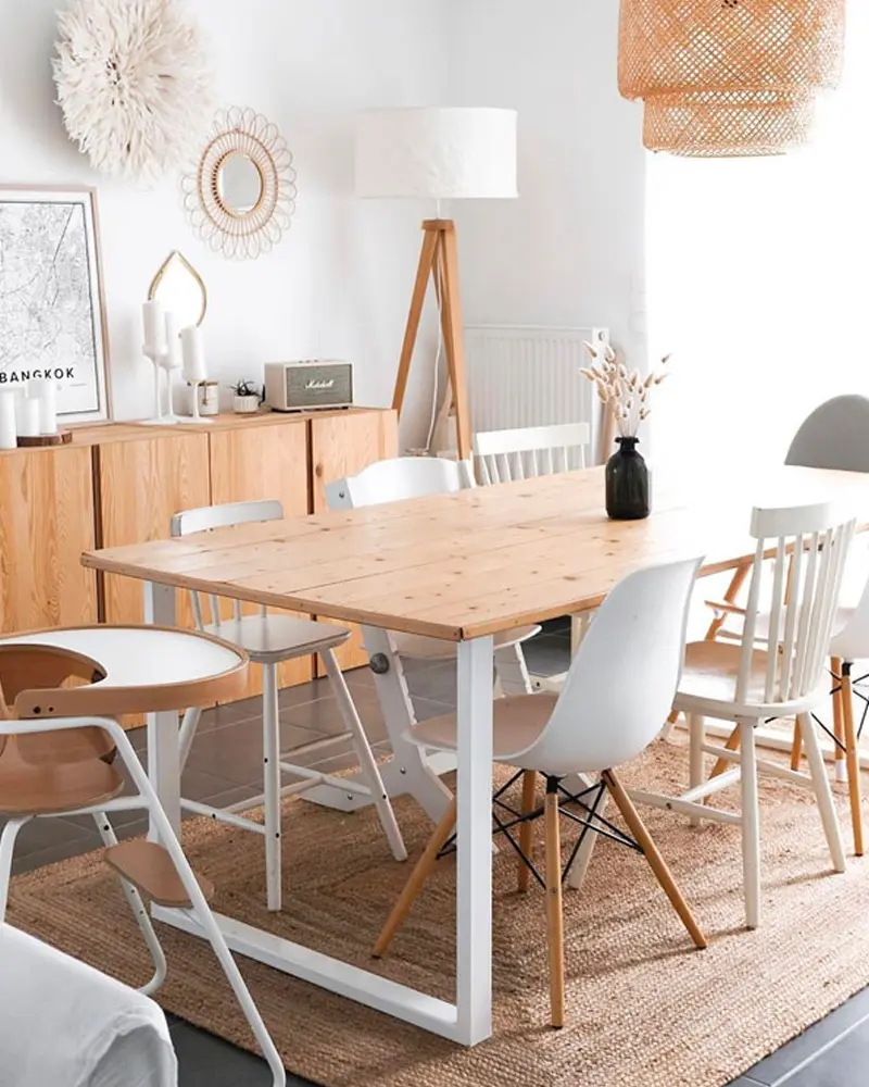 Pine table on a white metal base with mixed chairs, jute rug, rattan pendant and wood sideboard