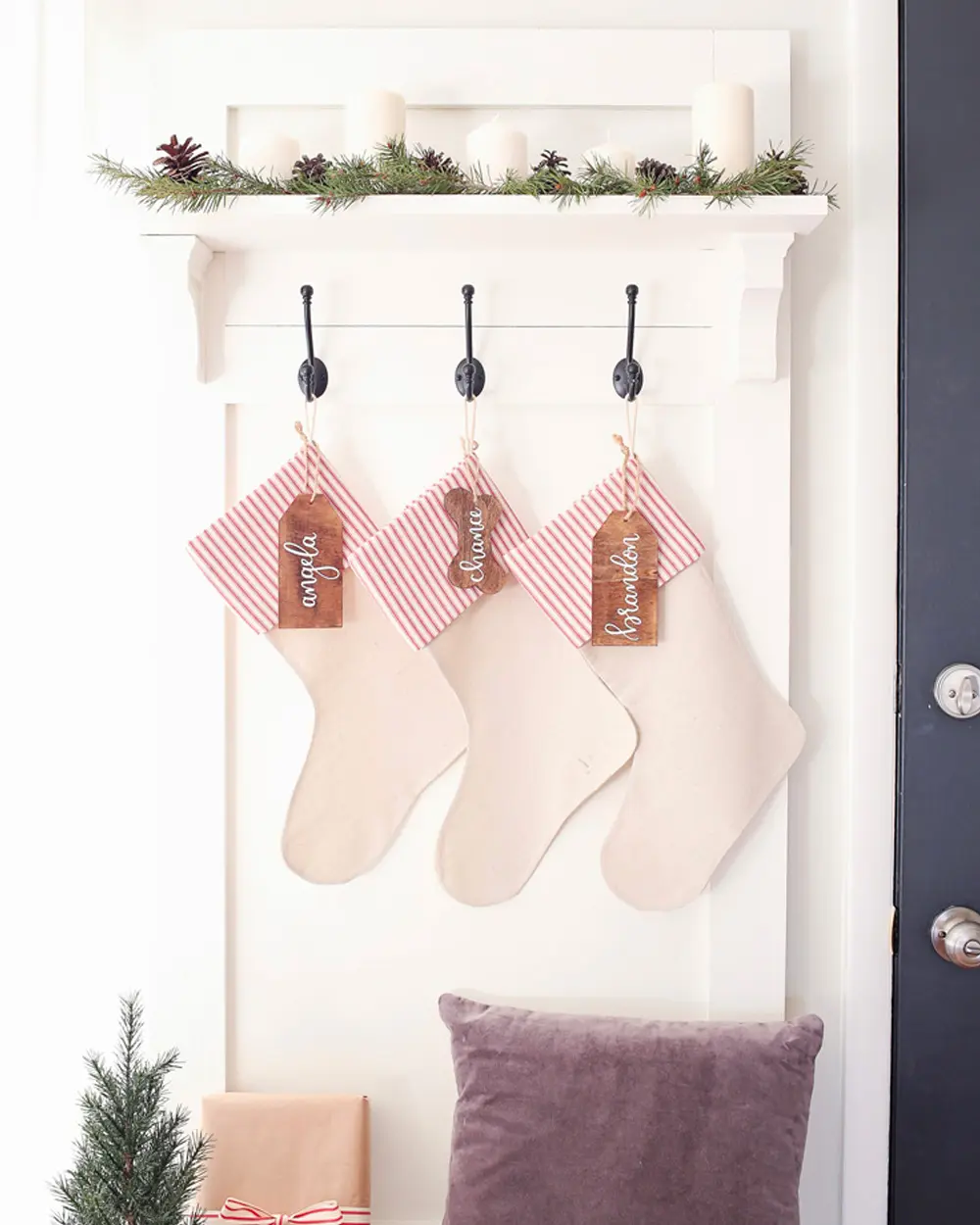 Three cream stockings with striped cuffs and wooden name tags hanging from black hooks