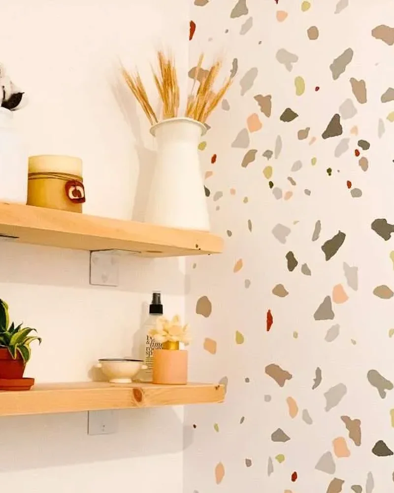 Wall painted with a terrazzo pattern next to wood floating shelves