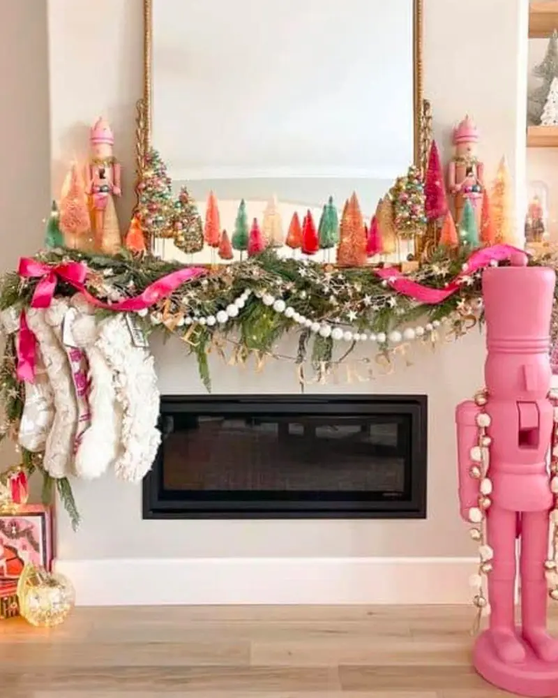Mantel lined with colorful bottle-brush trees, a pink ribbon and pearl garland, white stockings and a tall pink nutcracker