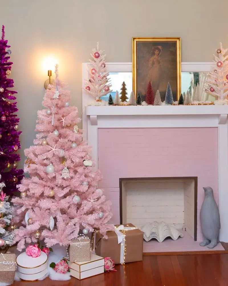 Fireplace with a pink painted surround, a pink Christmas tree, kraft-wrapped gifts and a framed portrait above
