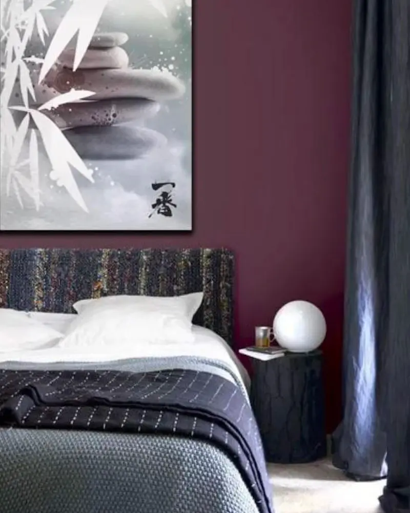 Bedroom with a deep plum wall, patterned headboard and gray bedding