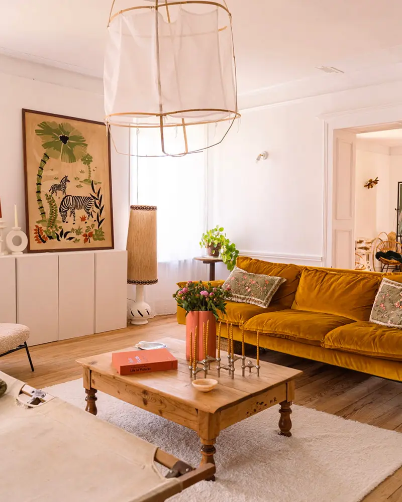 Mustard velvet sofa, wood coffee table, white cage pendant and framed zebra print