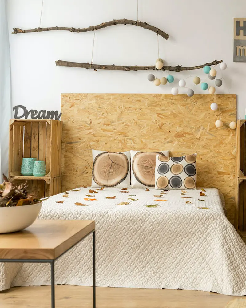 Bedroom with an OSB headboard, wood crate nightstand and branch with fairy lights