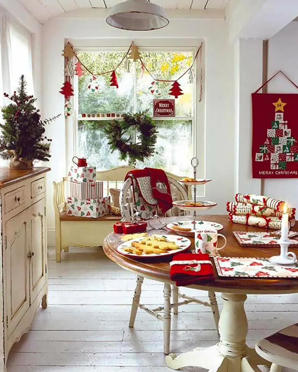 Cottage dining room with a red bunting garland, red patterned linens, holiday treats and a small tree