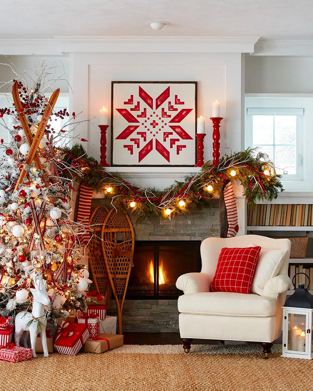 Living room with a red Nordic star print over the fireplace, red candles, a white armchair and garland