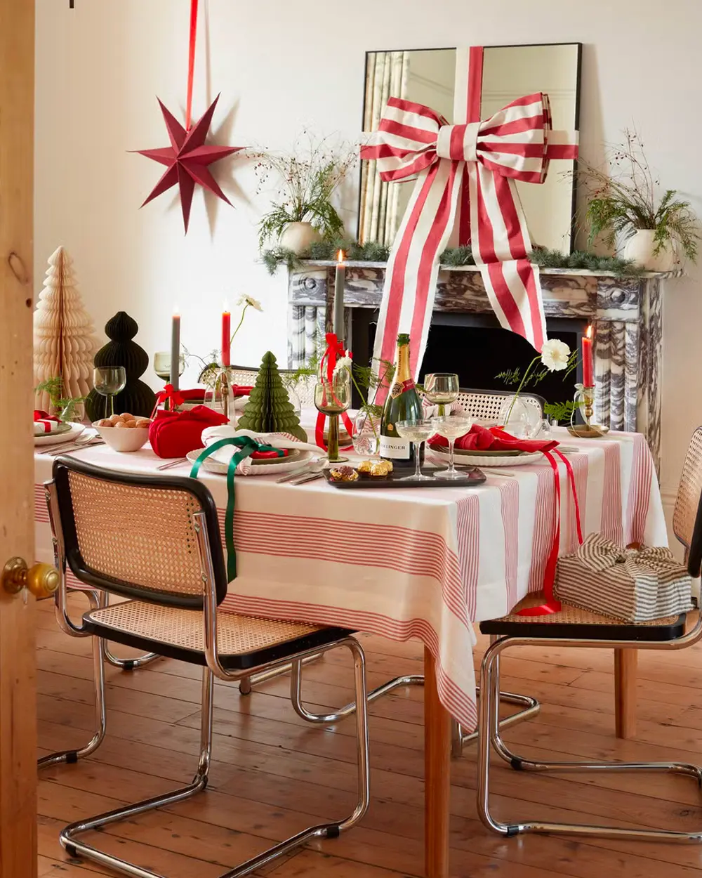 Dining table with a red and white striped tablecloth, giant striped bow on a mirror and red paper star