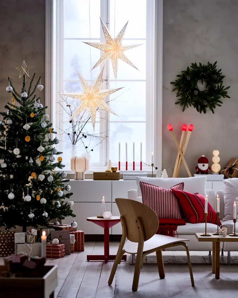 Living room with paper star lamps in the window, tree, red striped pillows and candles
