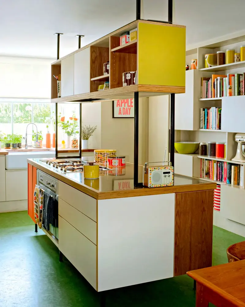 Kitchen island with yellow suspended cabinet, colorful bookshelves and green floor