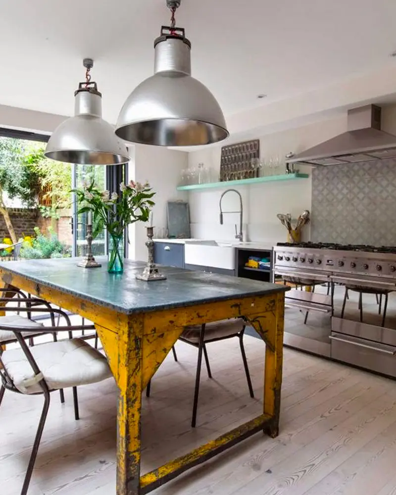 Yellow chipped-paint workshop table with a zinc top under two chrome dome pendants
