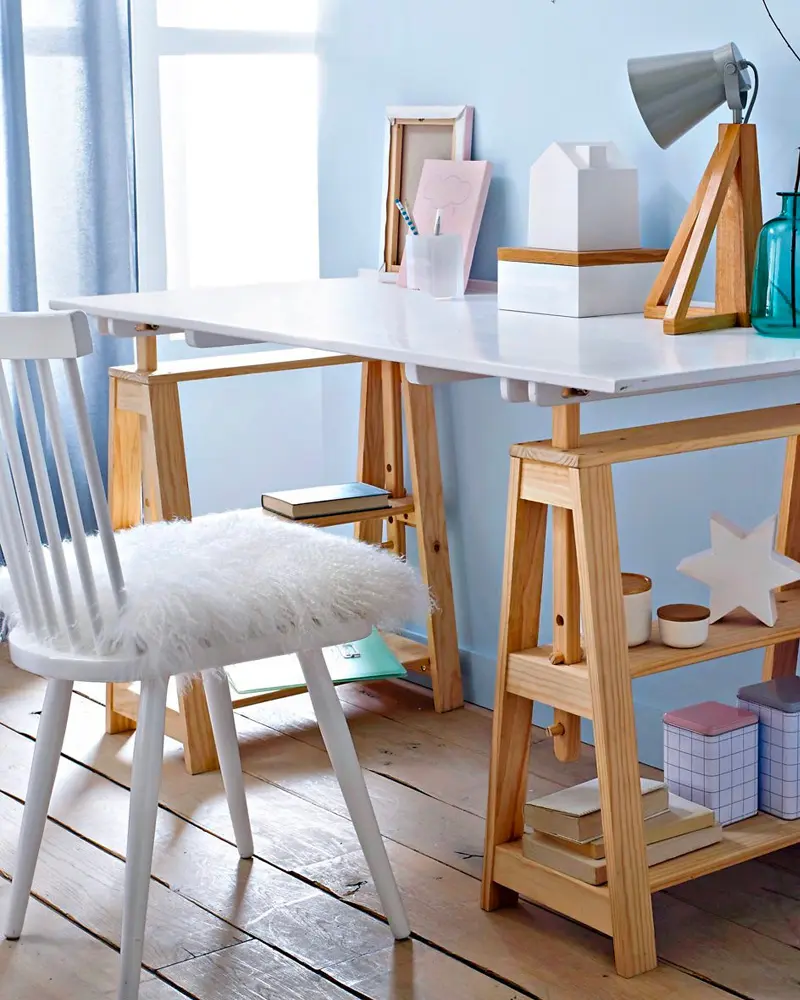White desktop on wood trestle legs with faux fur seat cushion on a white spindle chair