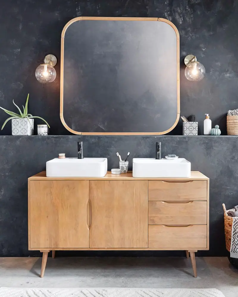 Mid-century wood sideboard used as a double vanity under a brass-framed mirror on a dark wall