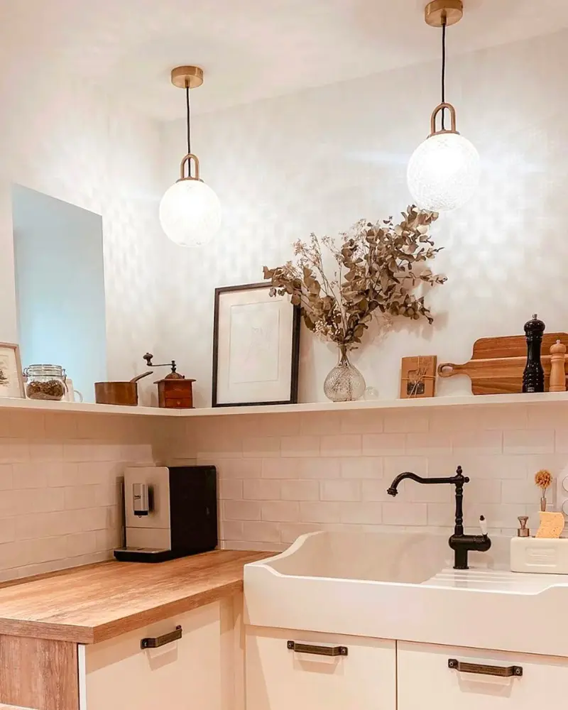 Small kitchen with wood counter, white farmhouse sink, black faucet, globe pendants and dried flowers