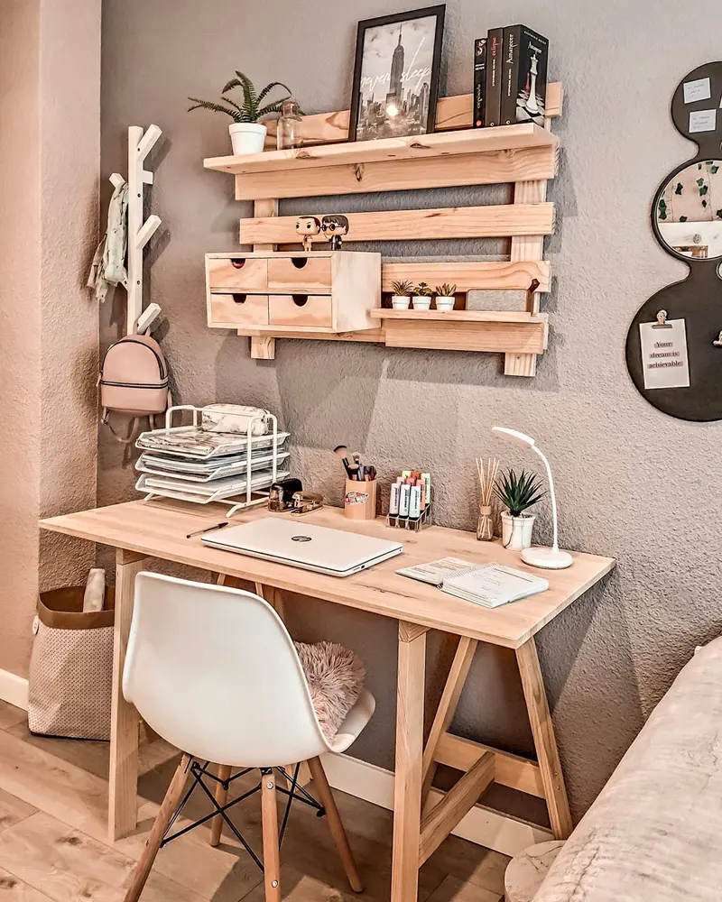 Light wood trestle desk with pallet-style wall shelves and plants