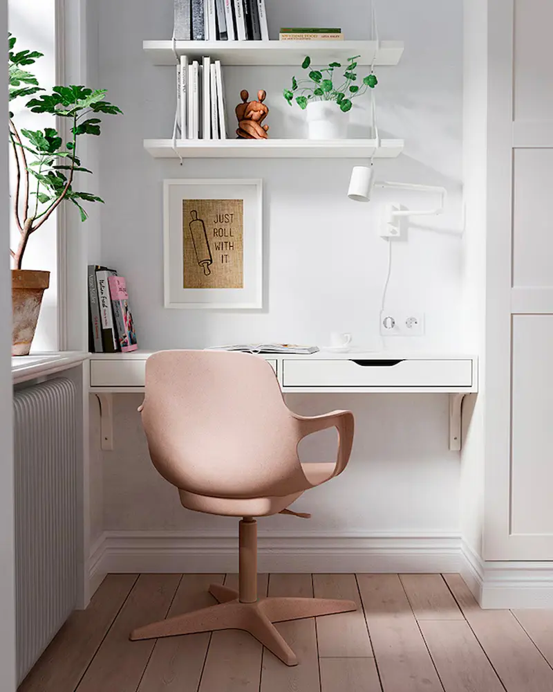 Floating white wall desk with blush swivel chair, wall shelves with books and plants