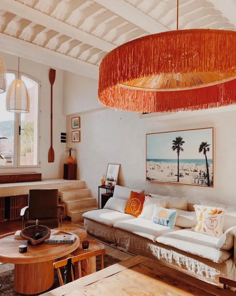 Long white daybed sofa with orange fringe pendant, beach print and wood coffee table