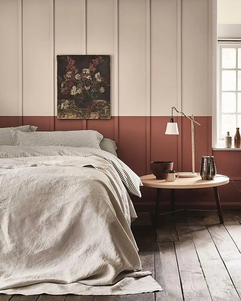 Bedroom with terracotta lower wall, cream paneling and linen bedding