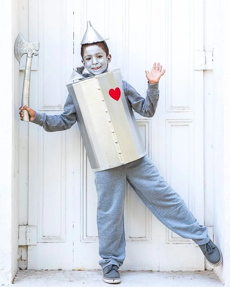 Boy dressed as the Tin Man with a silver body tube, funnel hat, red heart and toy axe