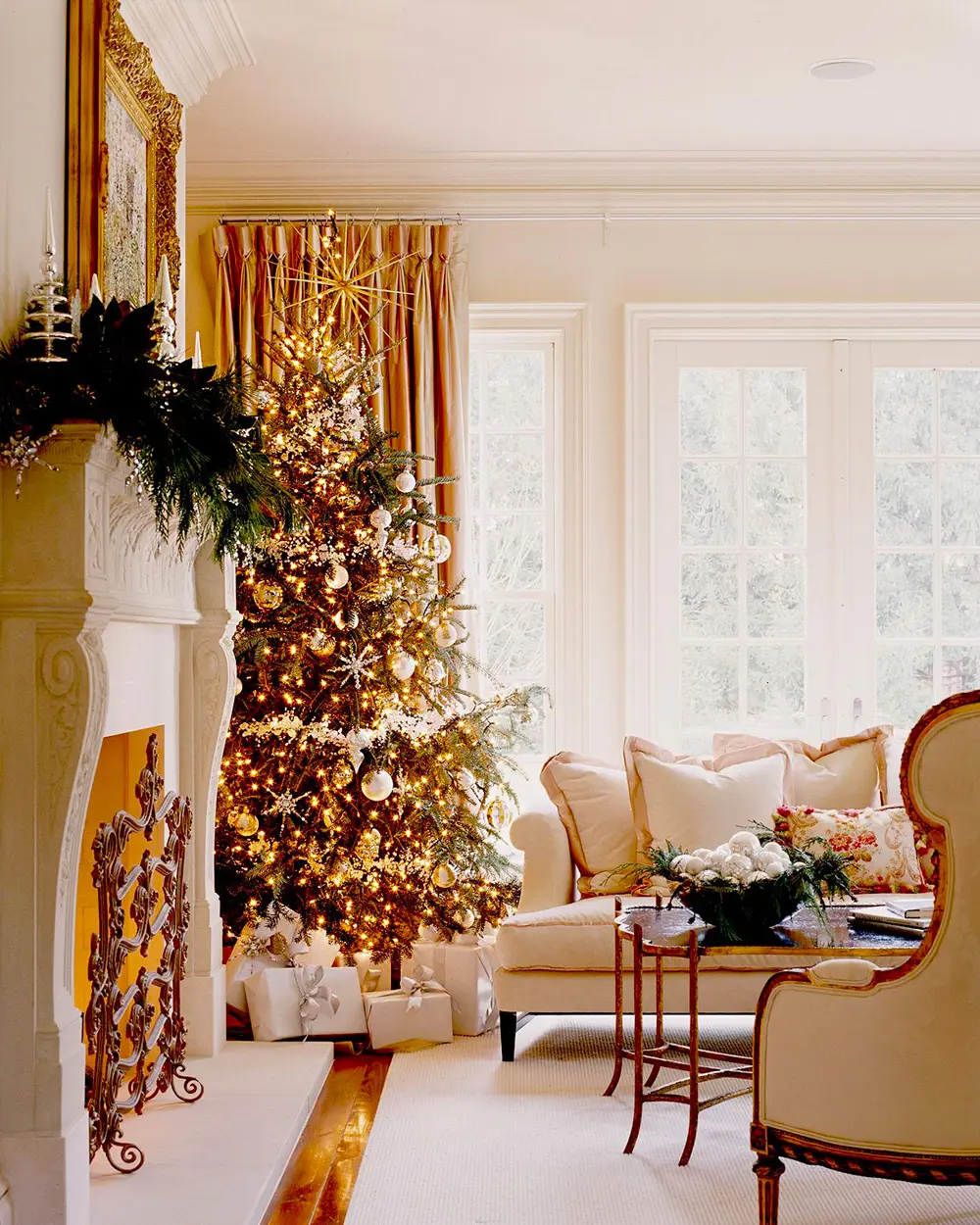 Cream living room with a heavily gold-decorated tree, gold curtains and a garland on the fireplace