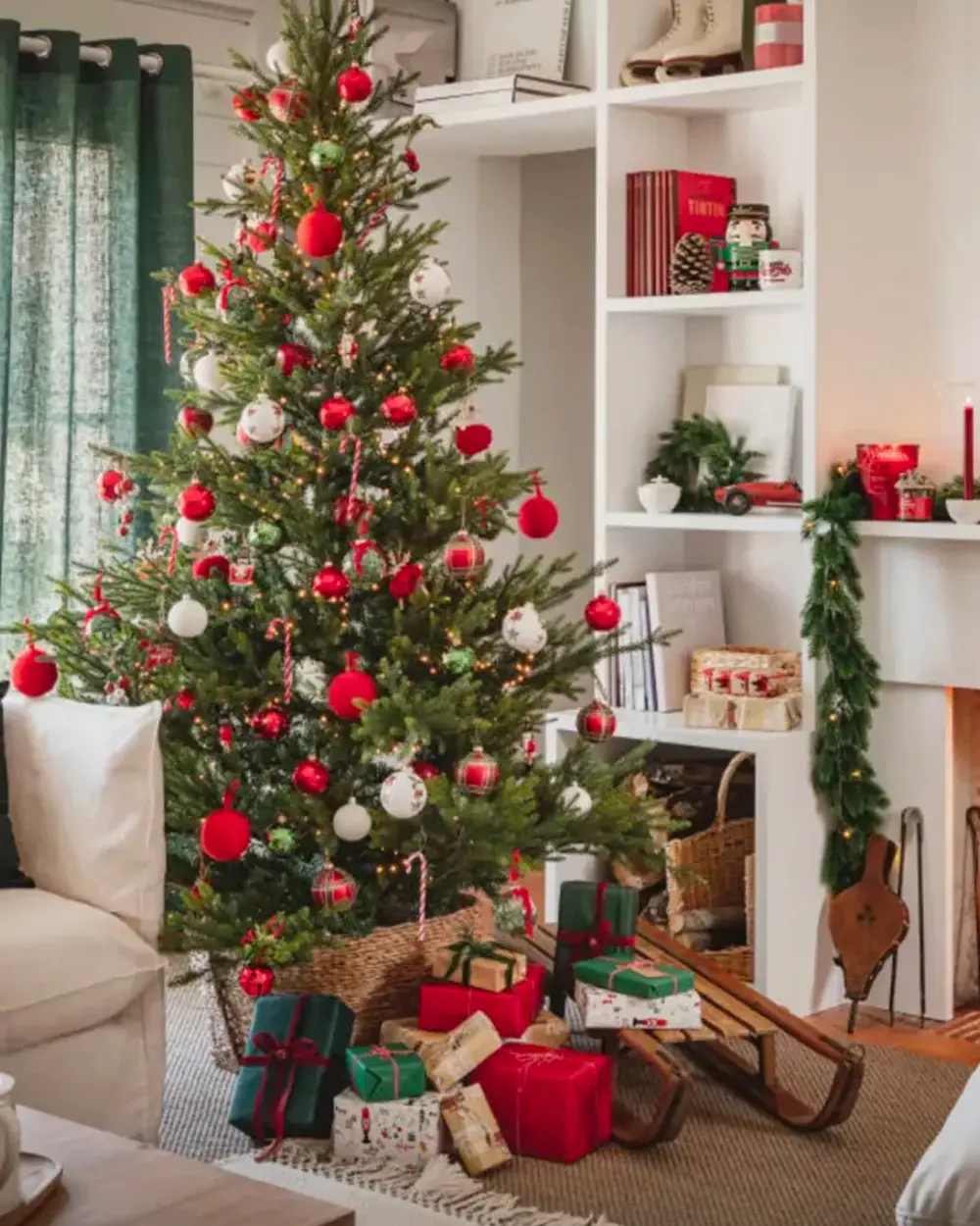 Living room with a green tree full of red and white ornaments, a wooden sled and wrapped gifts
