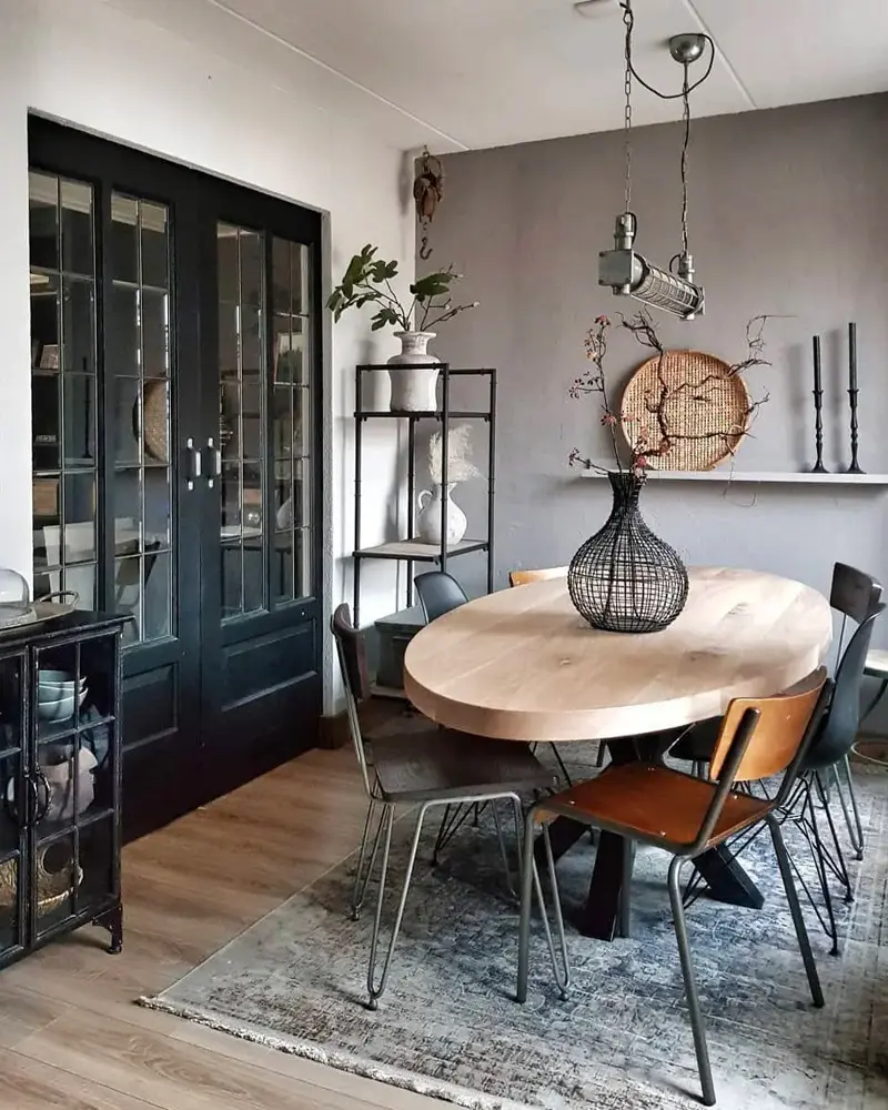 Round wood dining table with black metal chairs, black glass-front cabinets and a rug