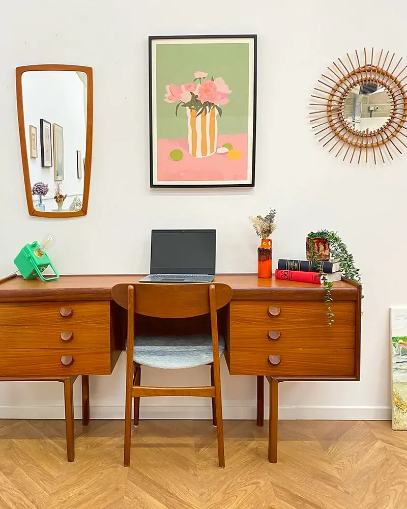 Mid-century teak desk with drawers, wood chair, rattan sunburst mirror and pink flower print
