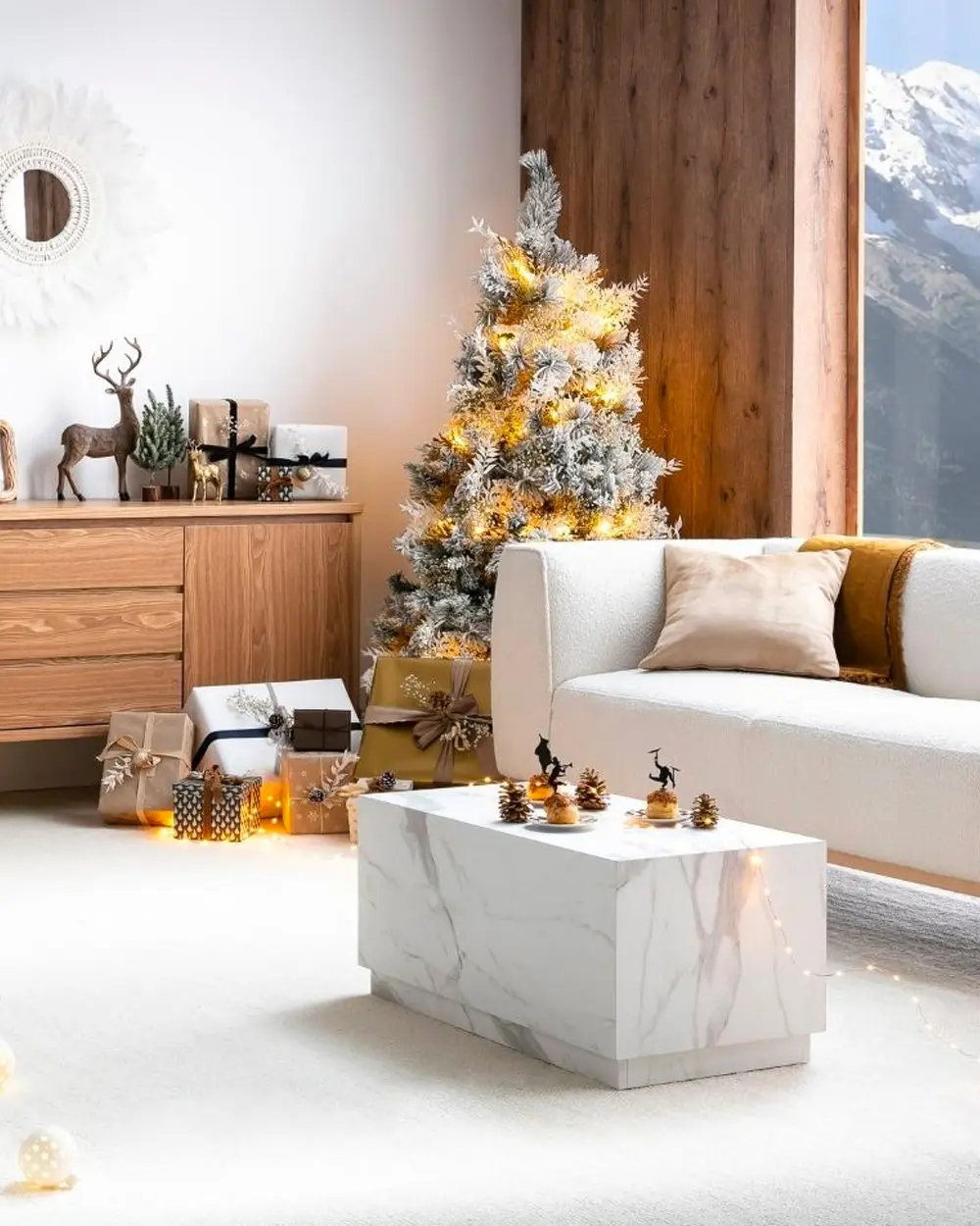 Modern living room with a flocked tree, white sofa, marble coffee table and a tall wood-clad wall with a mountain view