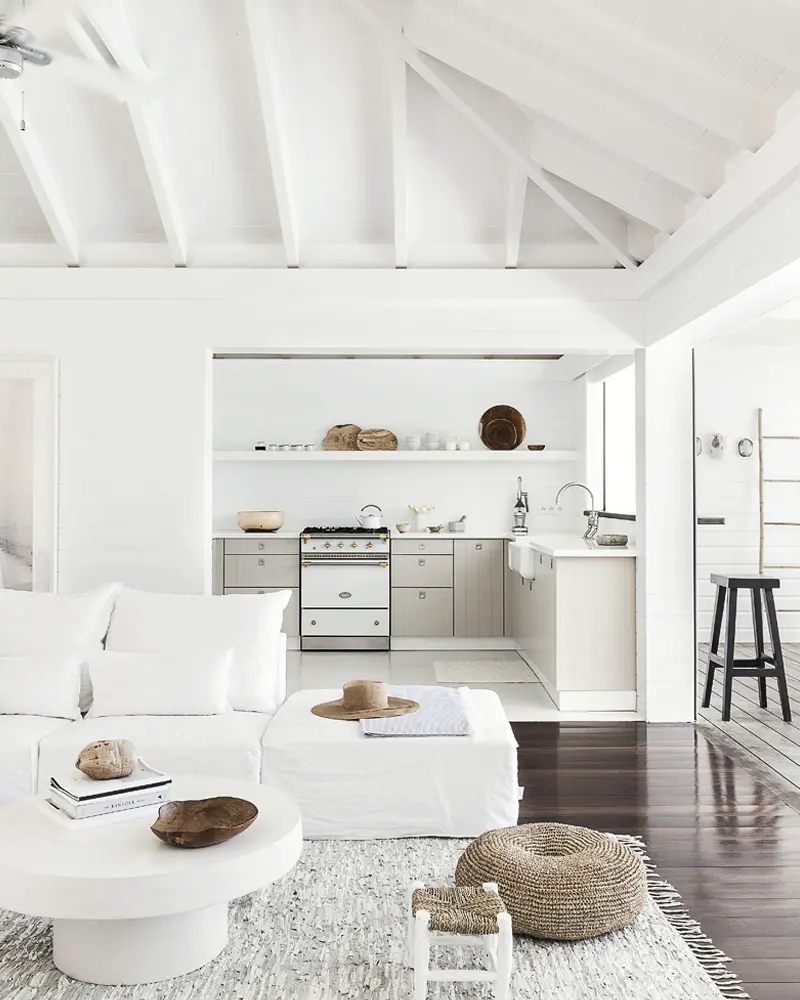 All-white living room with vaulted beams, white sofa and round coffee table