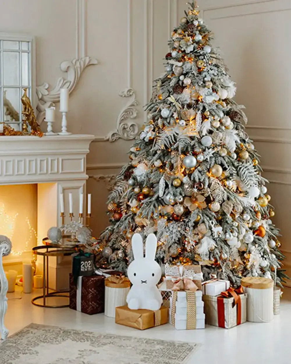 Flocked Christmas tree with white and gold ornaments, wrapped presents and a bunny lamp
