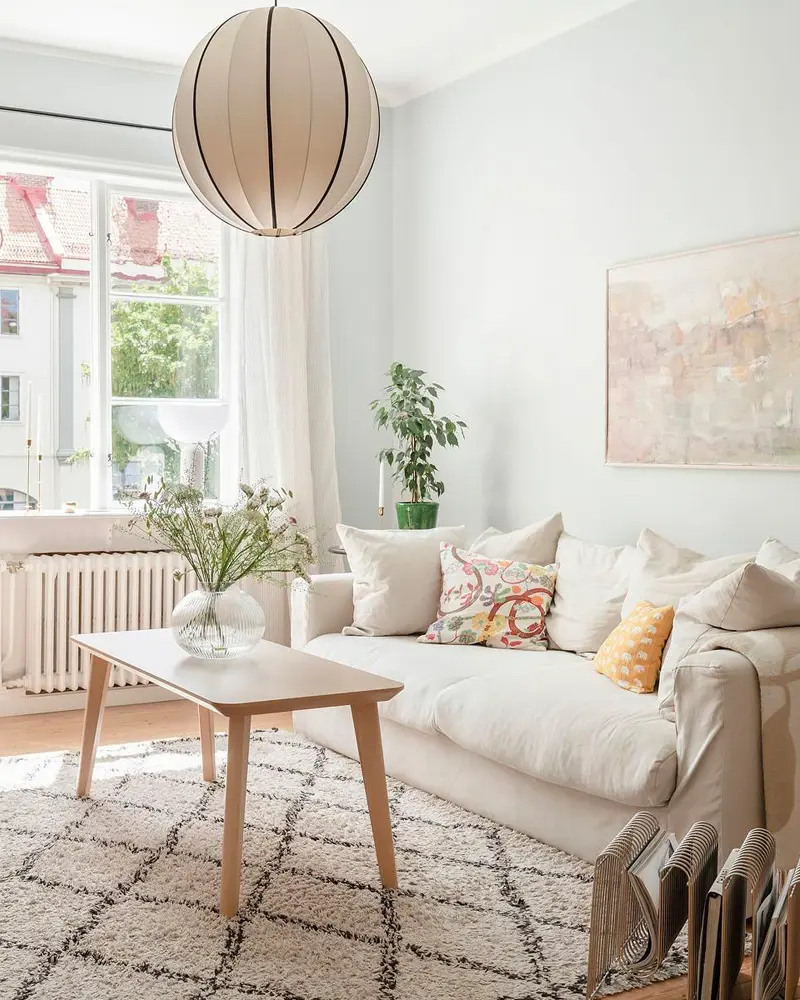 White living room with linen sofa, Berber rug and paper globe pendant