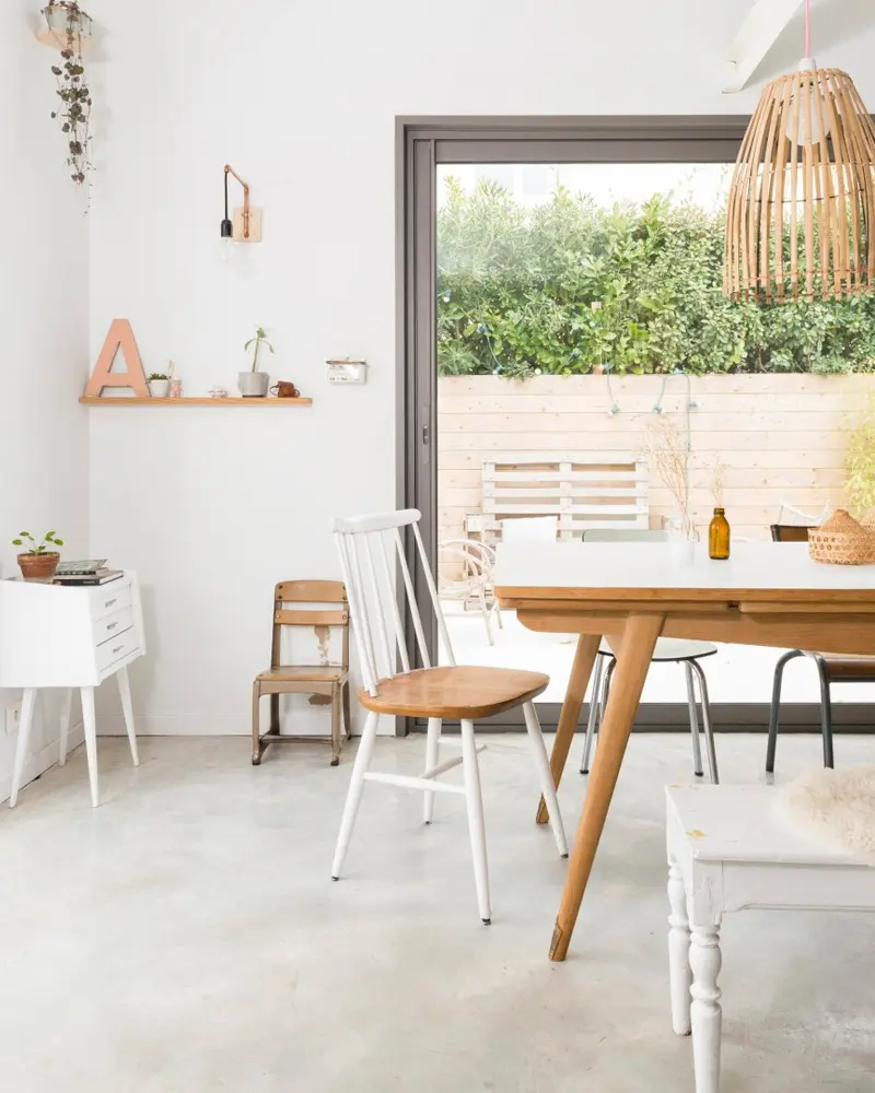White dining room with wood table, white spindle chair, bamboo pendant and garden view