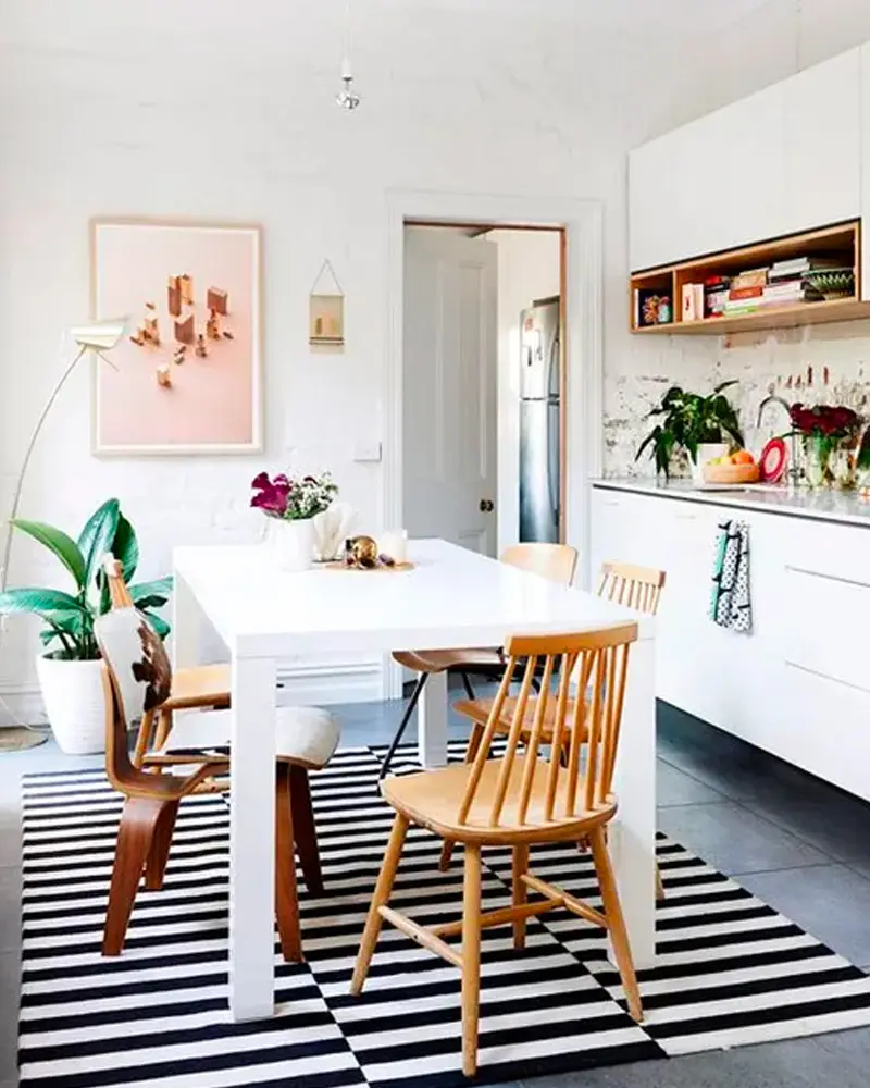 White table with mixed wood spindle chairs on a black and white striped rug