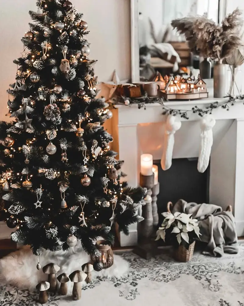 Dark green tree with gold and wood ornaments beside a white mantel with knit stockings and wooden mushrooms