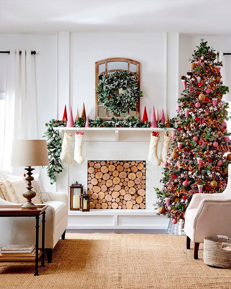 White living room with a red ornament tree, a log-filled fireplace, white stockings and pink paper trees