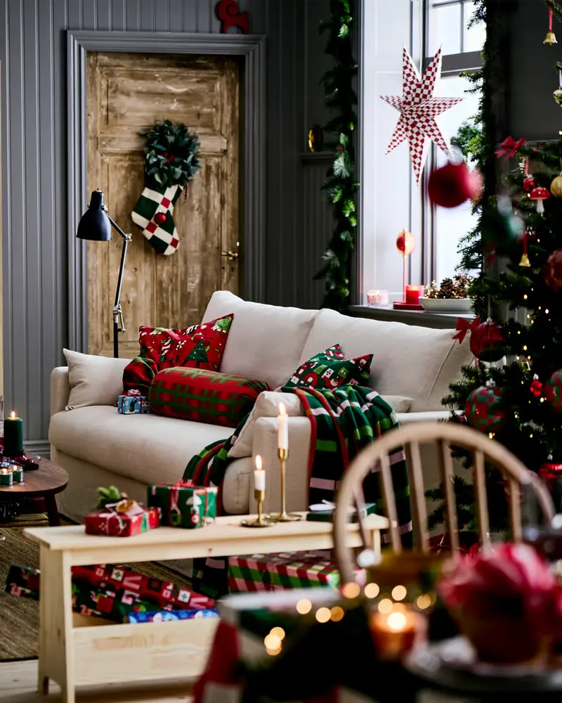 Wood door with a wreath, red and green plaid pillows, a paper star and a white Windsor chair