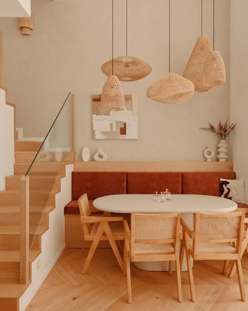 Terracotta banquette under rattan pendants with oval table and cane chairs