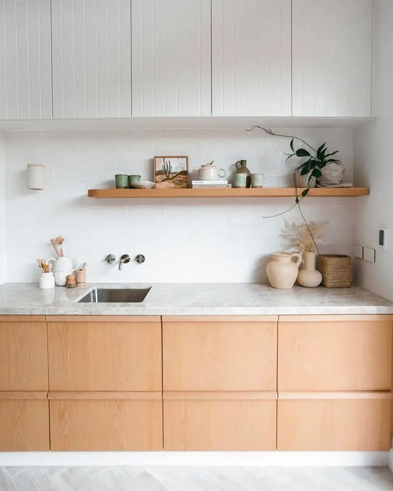 Light wood flat-front lower cabinets with white stone counter, floating wood shelf and ceramic vases