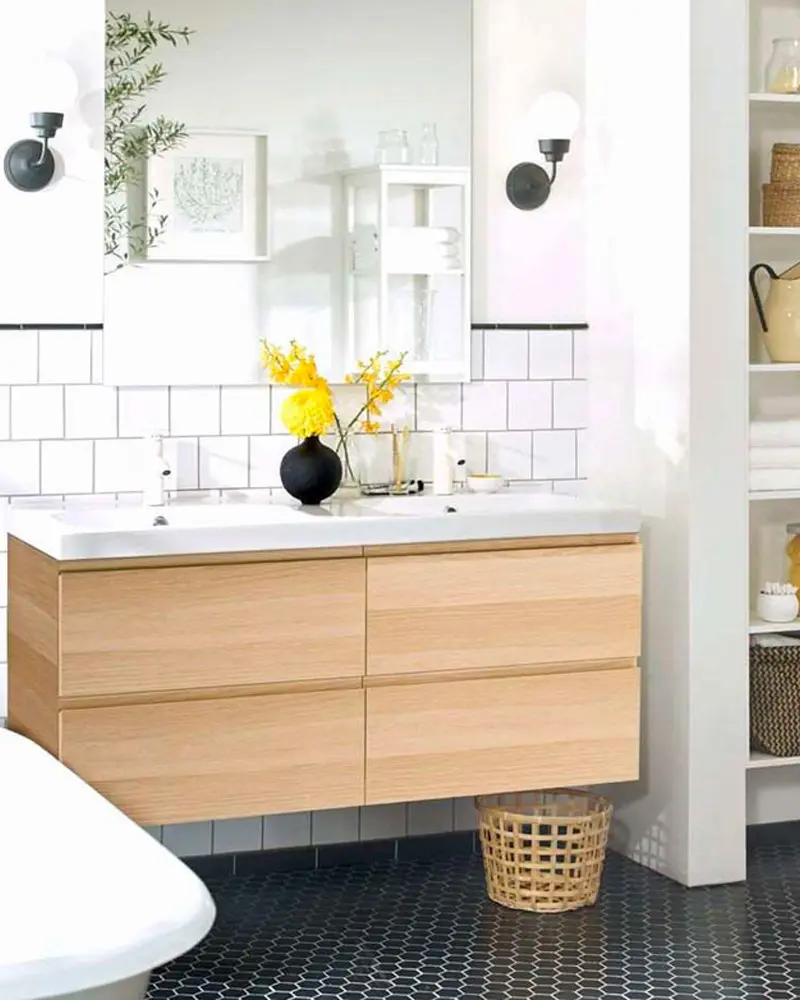Light oak double-drawer vanity with white top, yellow flowers, black wall lamps and navy hex floor